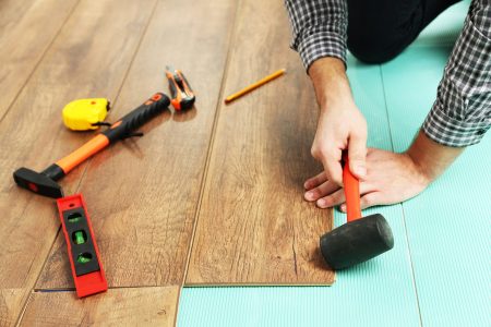 Carpenter worker installing laminate flooring in the room Carpenter worker installing laminate flooring in the room
